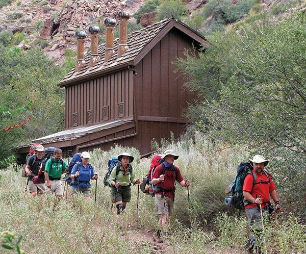 A backpacking party passes the Cottonwood Campground restrooms on the North Kaibab Trail.