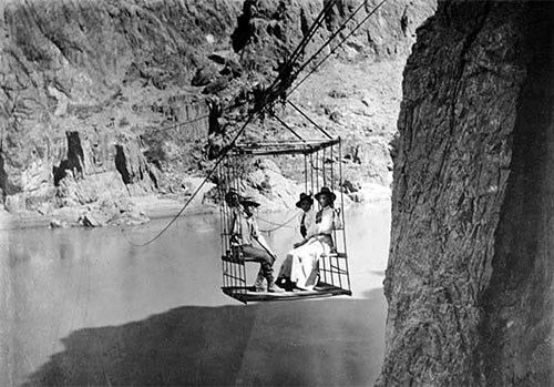 Rust’s aerial tramway crosses the Colorado River from south to north around 1908 with two women and one man riding as passengers in a cage.