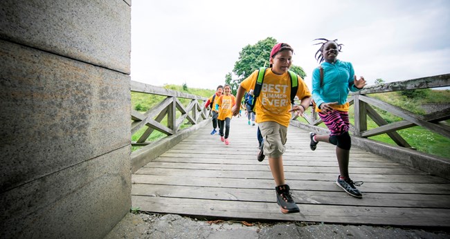 children running along a plank walkway entering a fort