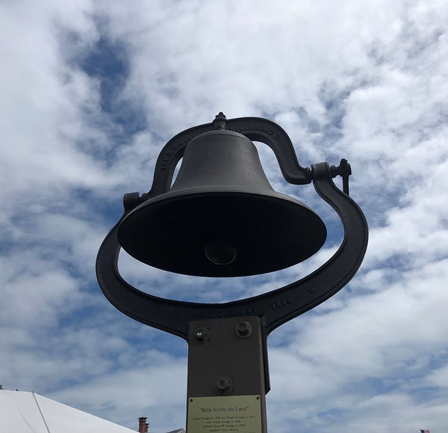 an iron bell with a blue sky behind it