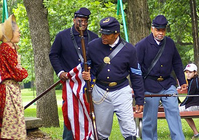 lt= Soldiers in Civil War Period Clothing march with the American Flag and rifles during a living history program at Freedoms Frontier National Heritage Area.