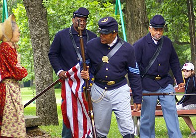 Soldiers in Civil War Period Clothing march with the American Flag and rifles during a living history program at Freedoms Frontier National Heritage Area.