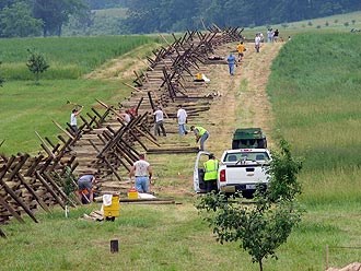 Gettysburg Foundation members build a long, wooden, criss cross style "worm" fence at Gettysburg National Military Park.