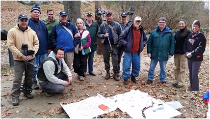 lt= Members of the Parker's Revenge Metallic Survey Team gather around project documents.