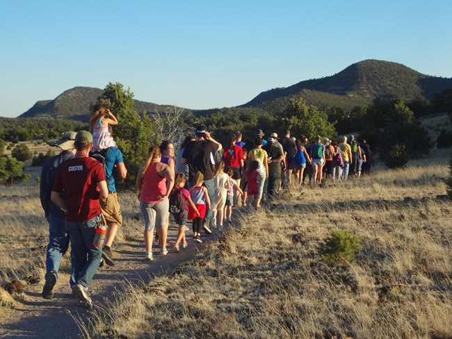 A line of visitors walk down a trail