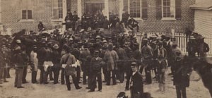 Crowd of white and black men in front of brick building