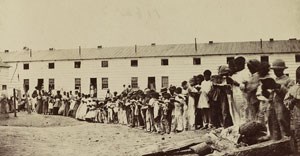 Black and white photo of crowd of African Americans in front of white building