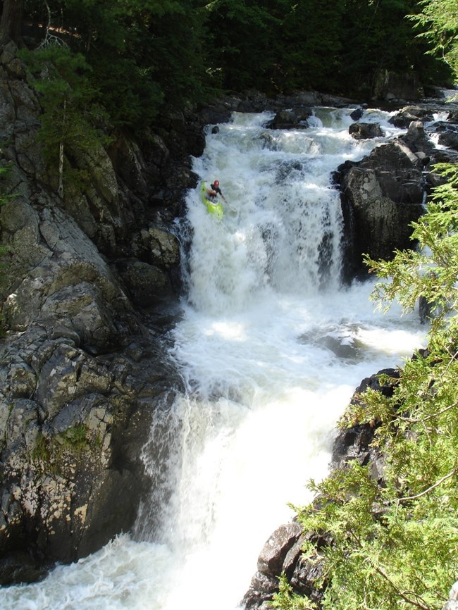 Boquet River River flowing over tiered rock formation with paddler on yellow kayak goiung down the rocks