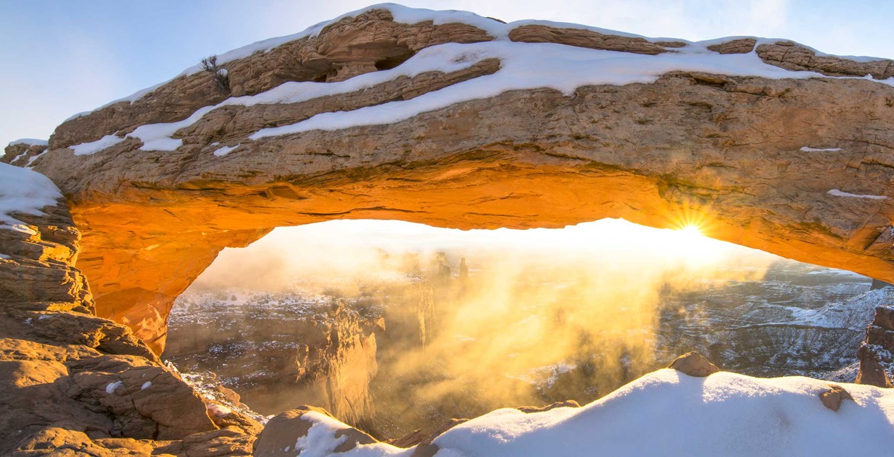 Rare solitude at Mesa Arch during a spring sunrise as clouds and fog lifted to reveal fresh snow on the arch and the spectacular canyon below.