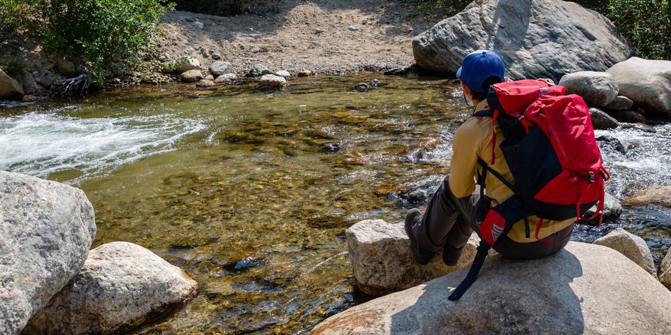 Hiker sitting on a rock near a river