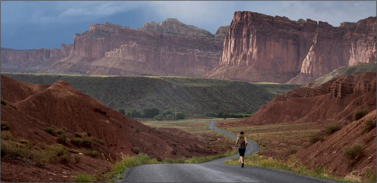 runner on a road through a spectacular red rock high relief landscape