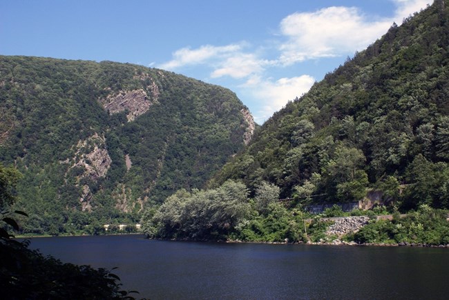 A body of water separates two tree-covered mountains.