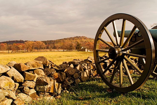 Civil war cannon in the foreground, with hills in autumn foliage in the distance
