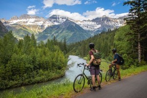 Two visitors look at mountains next to their bicycles