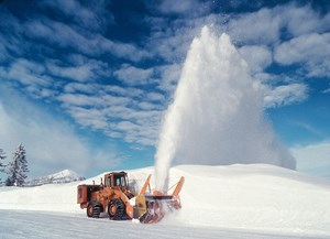 A snowplow blowing snow off of a road