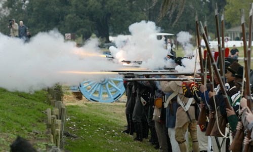 Re-enactors in soldier uniforms firing muskets