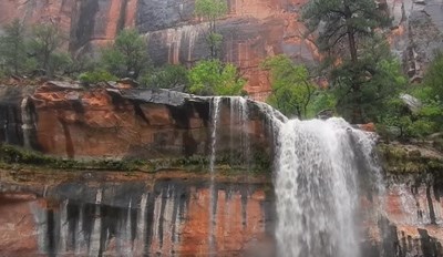 Waterfall Frontal view of a waterfall over red rock framed by forest.