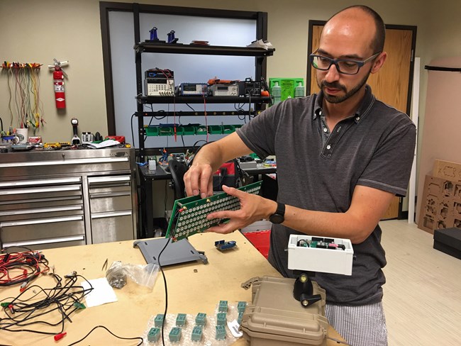 NPS acoustic technician Damon Joyce shows some of the electronic components that comprise the noise level display signs.