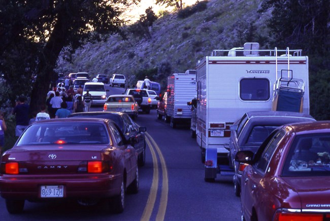 Bumper to bumper vehicles crowd a park road