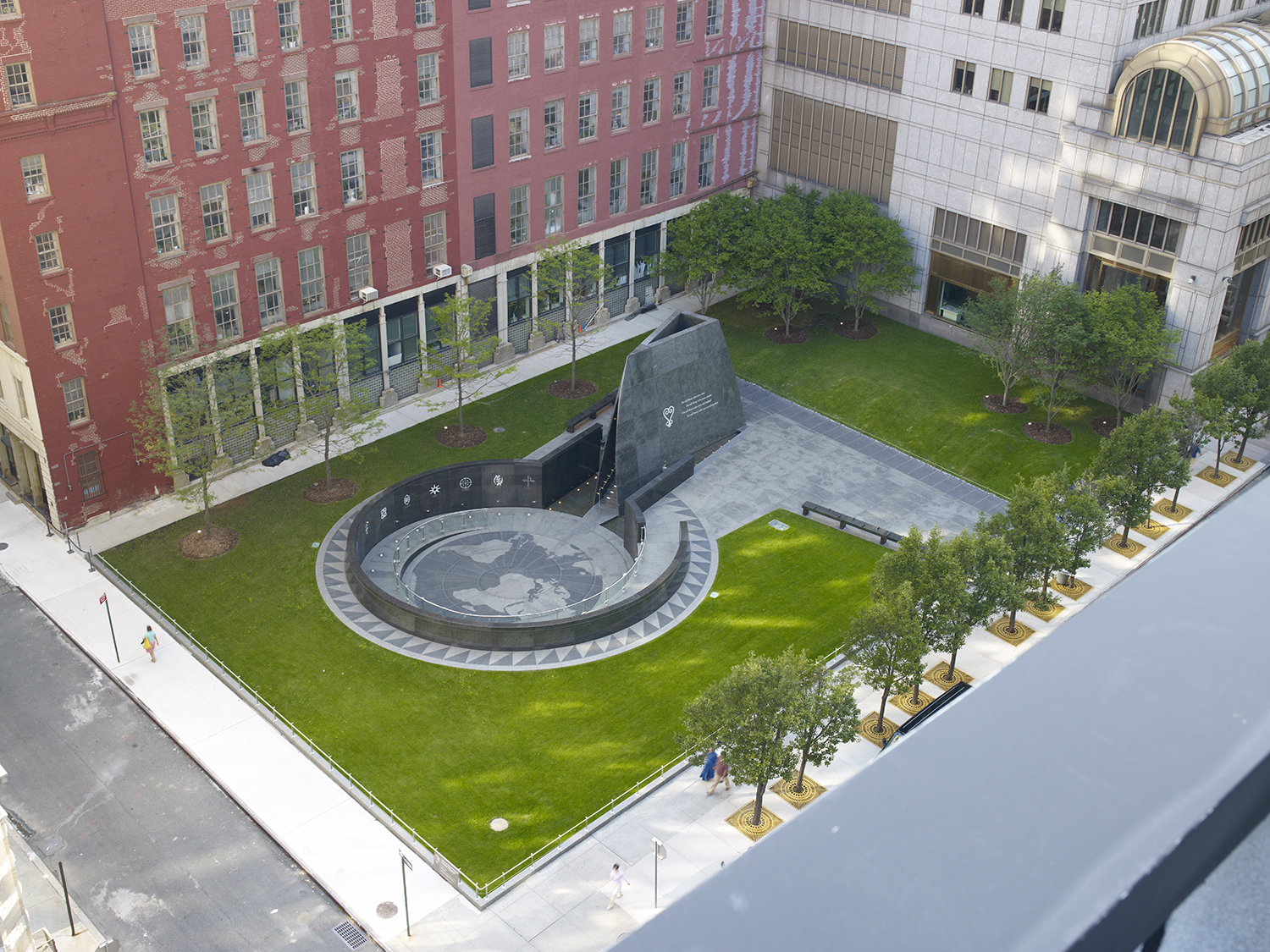 Photograph of African Burial Ground National Monument in New York City by Carol M. Highsmith. Stone monument surrounded by a lawn and tall city buildings.