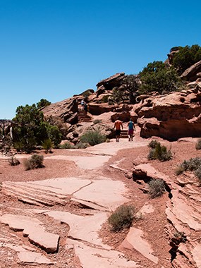 hikers in the distance hiking up red rocks