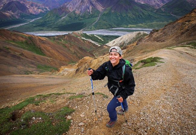 Hiking for health a hiker with hiking poles smiles at the camera while ascending a steep mountain slope