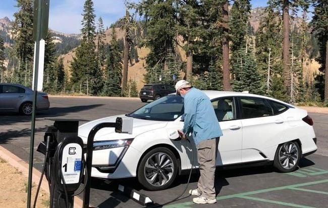 lt= A person charging their electric vehicle at a park
