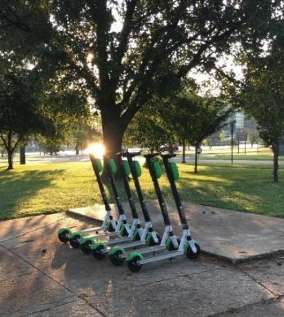 six E-Scooters lined up in a park setting