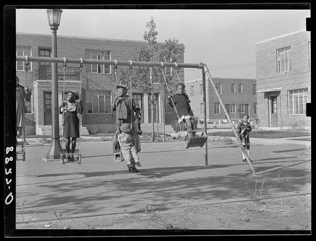 Laughing, smiling children on swings. Believed to be at Logan Fontenelle Housing Project.