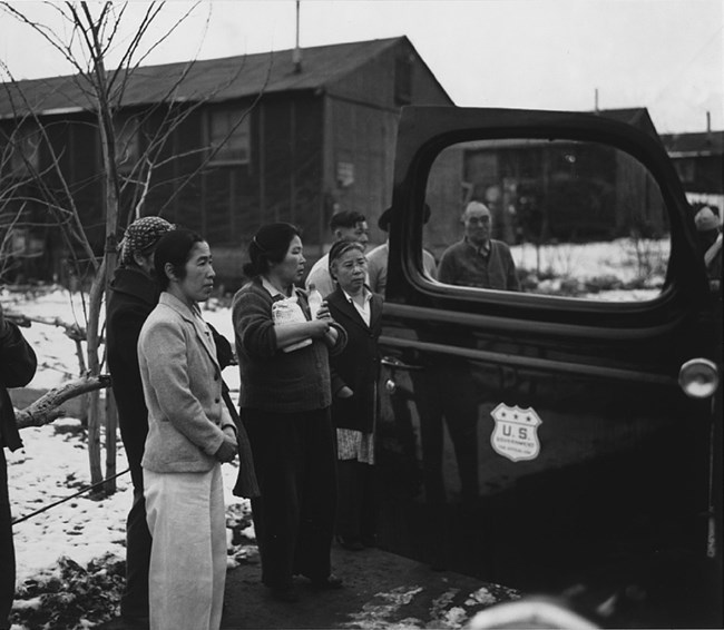 Group of women standing, facing right, near the open door of an automobile, buildings in the background.Library of Congress. Group of women standing, facing right, near the open door of an automobile, buildings in the background.
