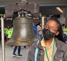 Photograph of Devynn Chester wearing mask with the Liberty Bell behind her
