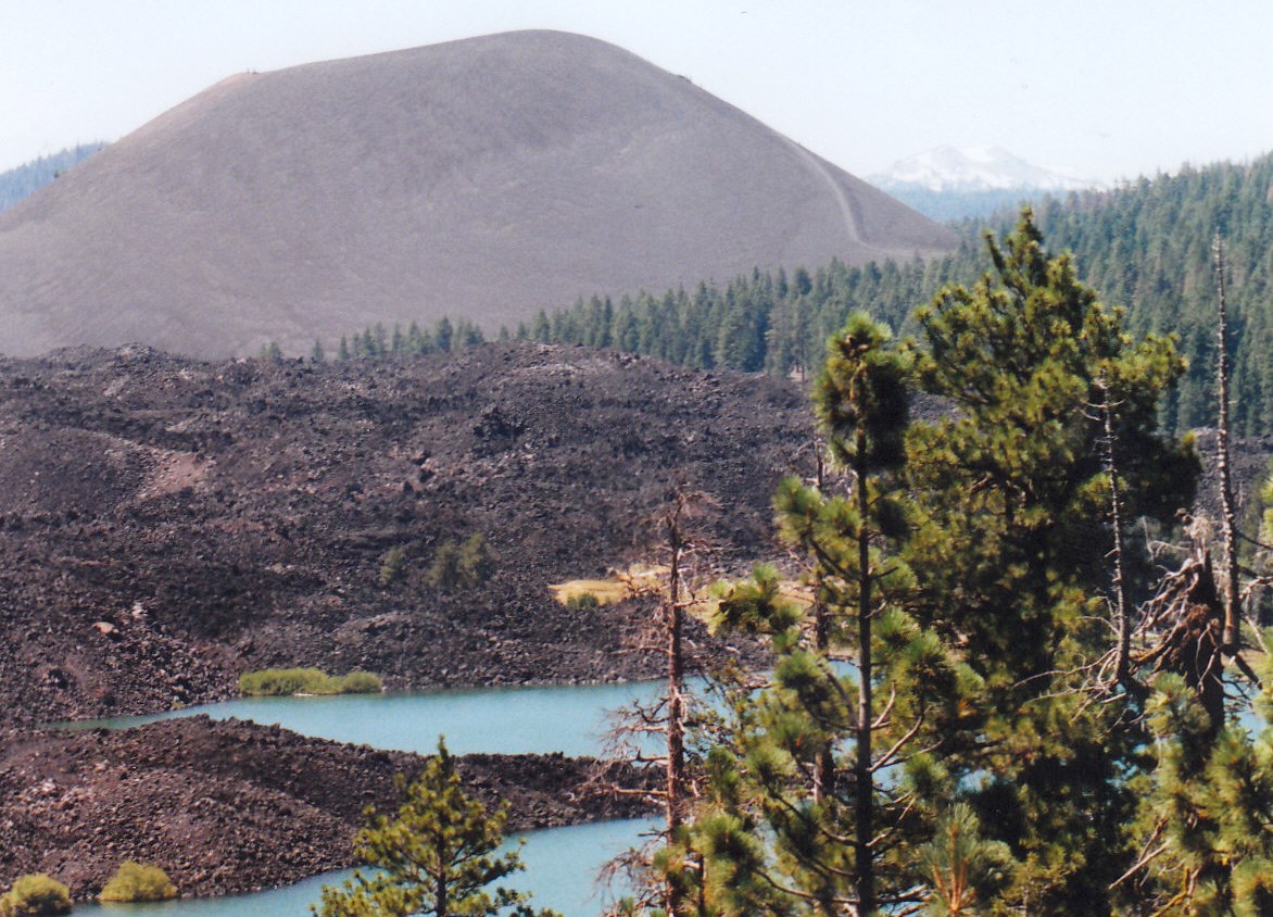 photo of a lava flow, lake, forest and volcanic cone