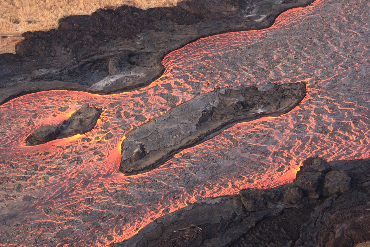 Aerial photo of molten lava flowing in a channel.