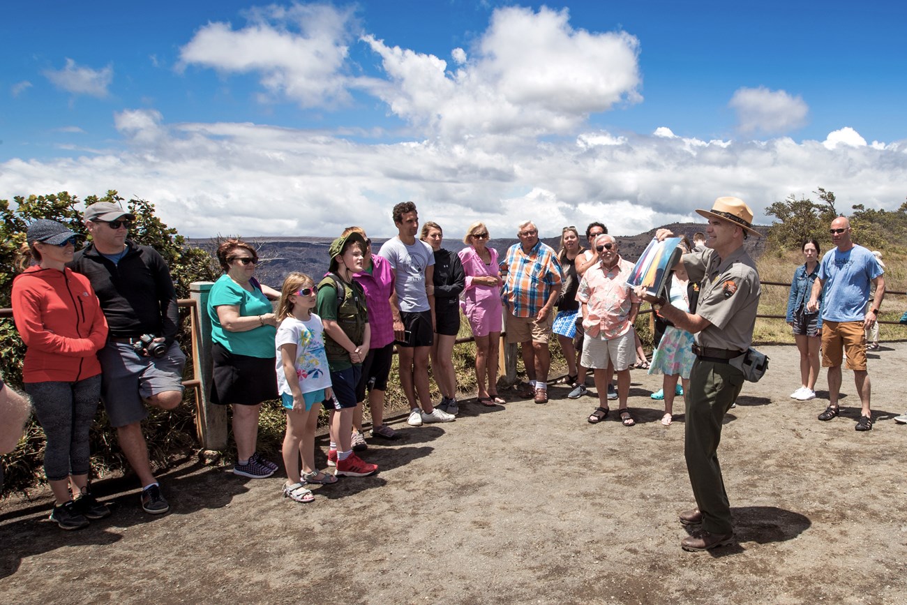 Photo of a park ranger talking to a group of visitors at a caldera rim viewpoint.