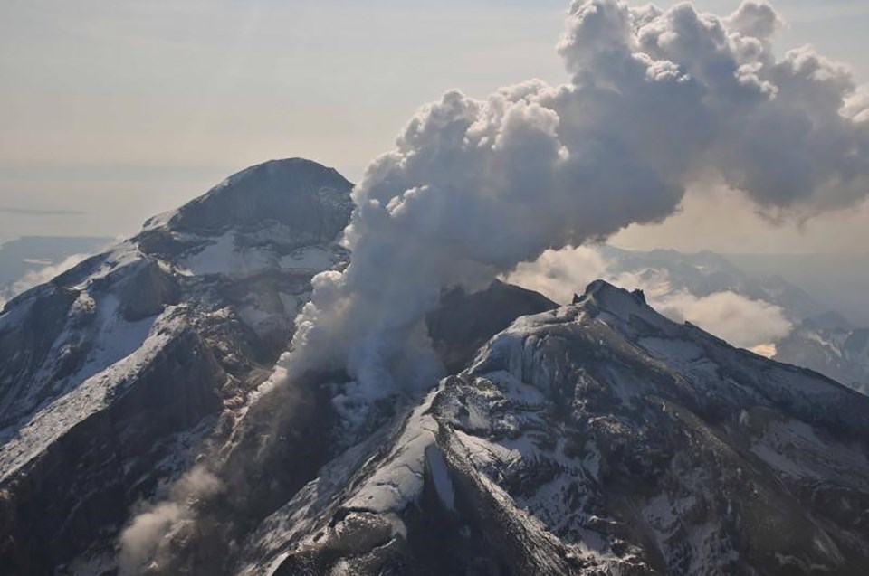 steam cloud rises from an erupting mountaintop crater