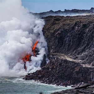 photo of molten lava flowing into the ocean and producing a plume of steam