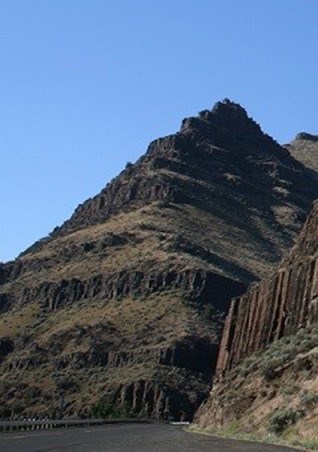 photo of hillside with banded rock layers of jointed basalt