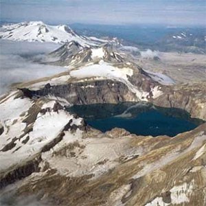 aerial view photo of a crater lake and a snow-covered peak in the distance