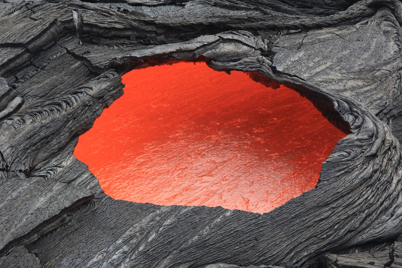 vhp_img4391 Photo of a hole in hardened surface lava where molten lava can be seen flowing beneath.