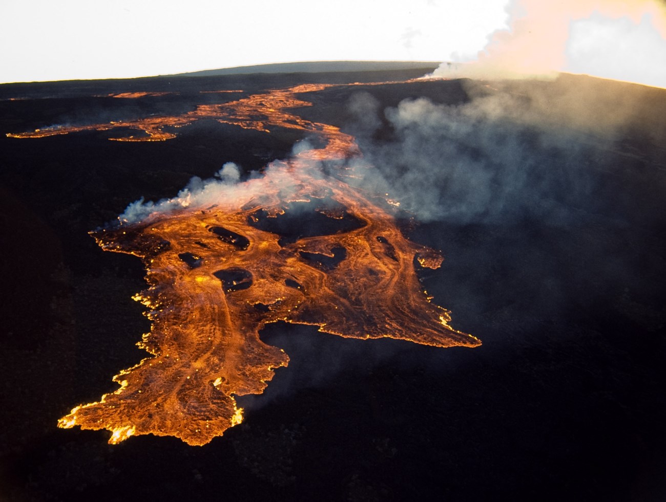 Photo of molten lava flowing across the ground.
