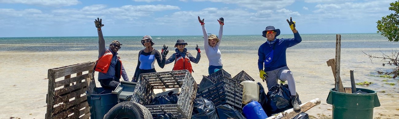 A group of volunteers pose with trash they cleaned up on a beach.