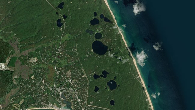 a satellite image of the Cape Cod coastline with over a dozen small kettle ponds on the inland shore