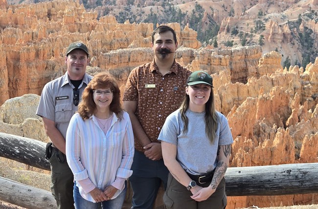 Award recipients from the Bryce Canyon Employee Safety, Health, and Wellness Committee. Four people stand in front of a geologic overlook.