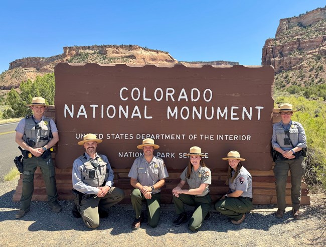 Award recipients from Colorado National Monument. Six people stand in front of the Monument's entrance sign wearing NPS uniforms.
