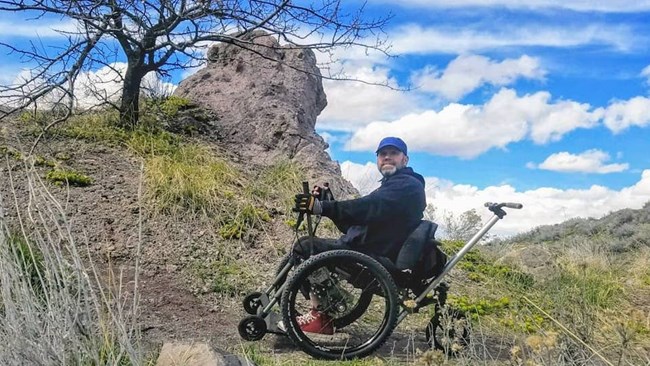 A wheelchair user takes in the hillside view. A wheelchair user takes in the hillside view.