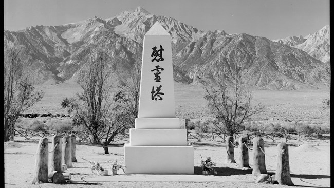 White obelisk with Japanese characters and mountains in background