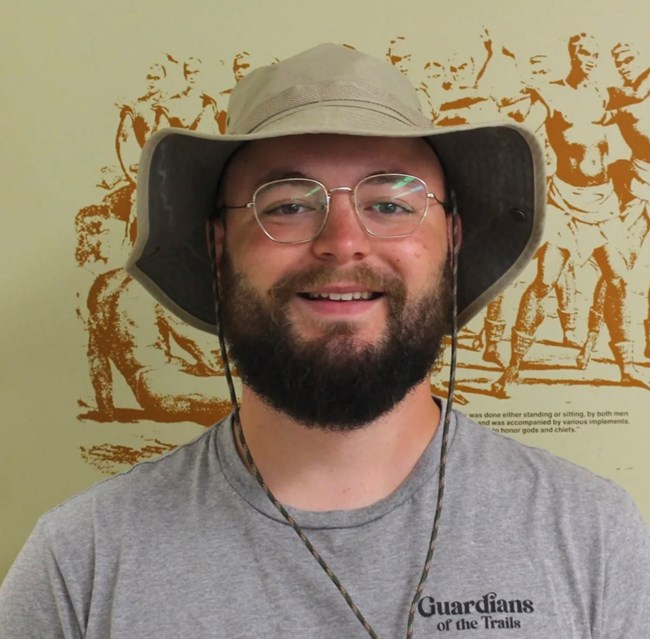 A man smiling, wearing a hat