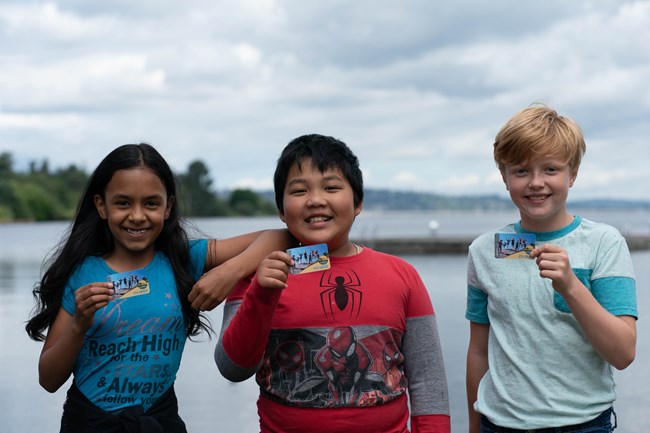 Every Kid Outdoors Photo Three 4th grade students hold up Every Kid Outdoors passes