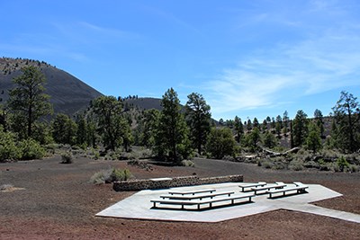 a concrete seating area situated among volcanic cinders at the base of a cinder cone volcano
