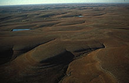 Grass covered hills have sharp layers from differential erosion.
